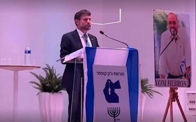 Israeli Finance Minister Bezalel Smotrich speaking in Paris behind a podium bearing a Greater Israel map that incorporates modern Jordan